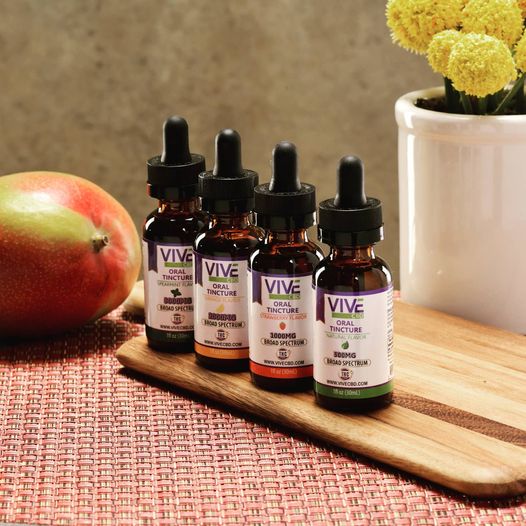 Serene spa-like scene with lush hemp plants and ViveCBD products including roll-on, honey sticks, pet tinctures, gummies, bath bombs, and vapes.